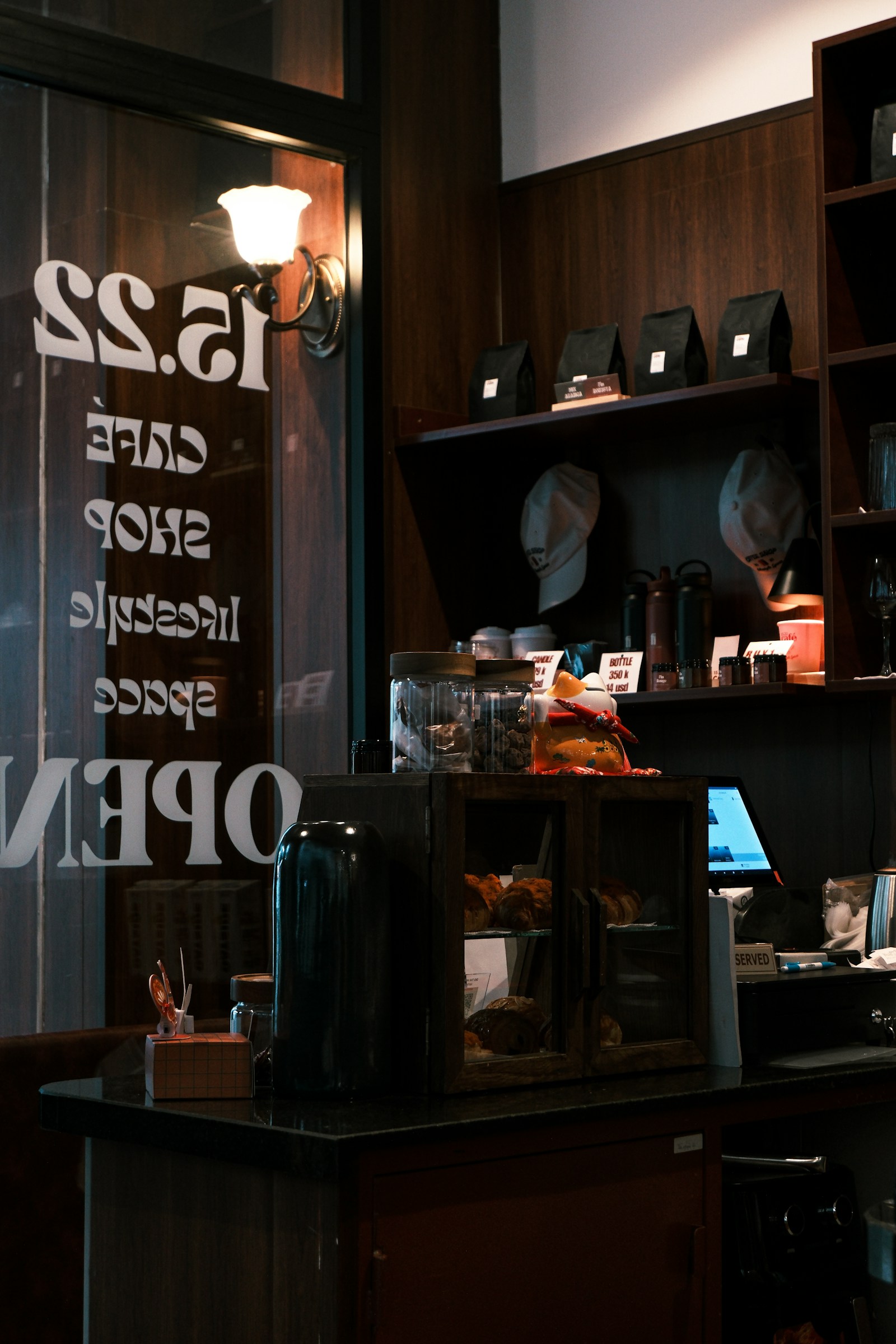 A warmly lit wooden coffee counter with pastries and bags of beans