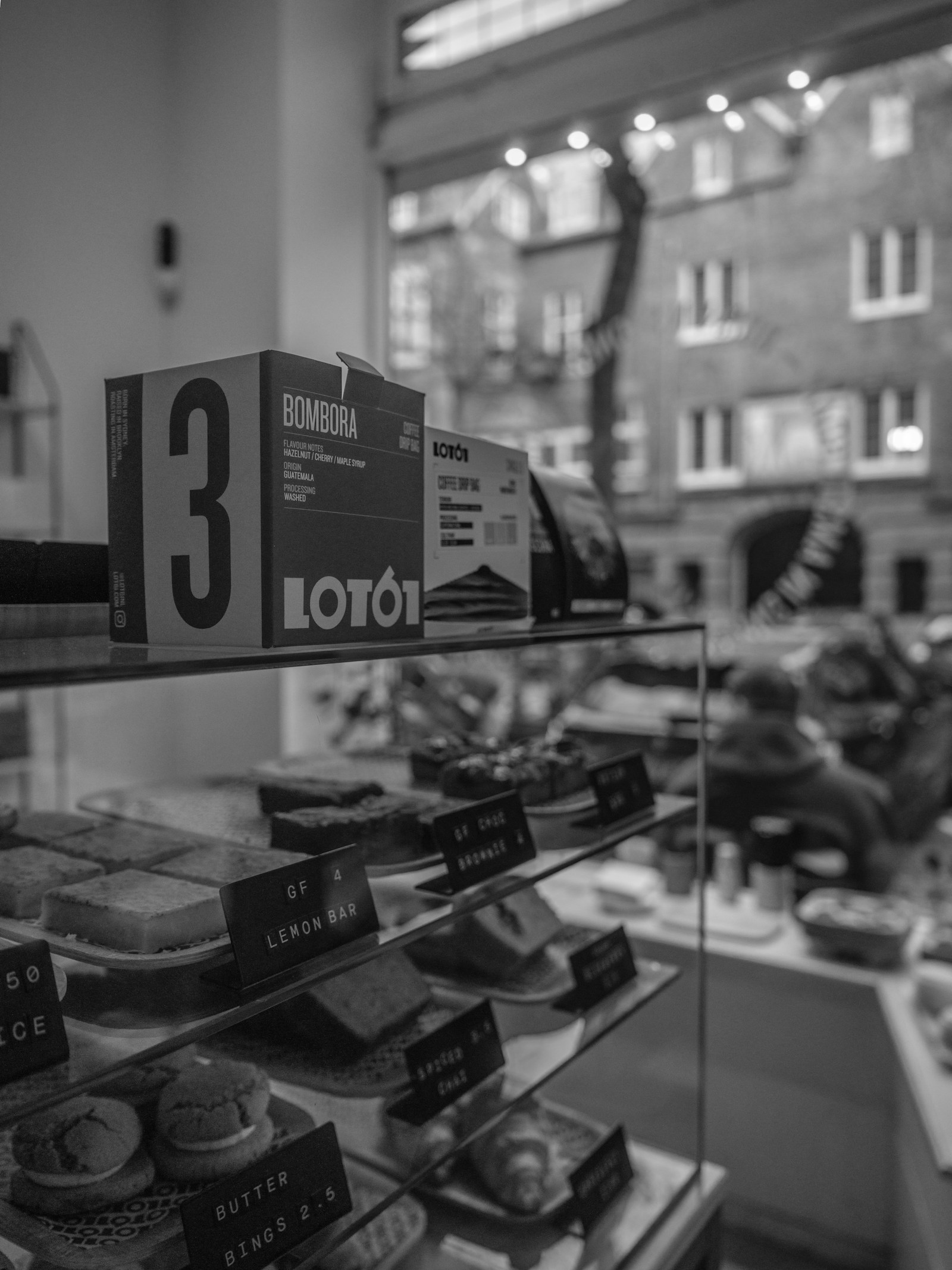 Black-and-white photograph of cakes and coffee boxes in a café display